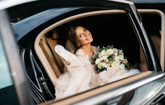 bride sitting in a limo holding flowers
